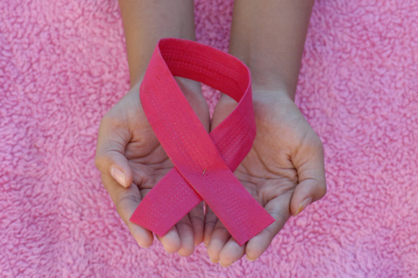 Hands holding a pink ribbon