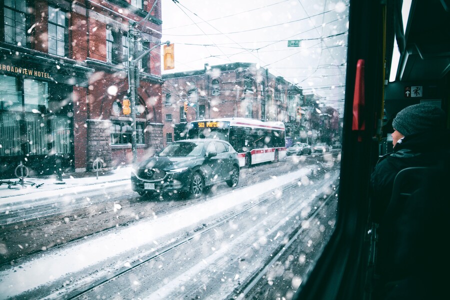 A wintery view out of a streetcar window of the road full of cars