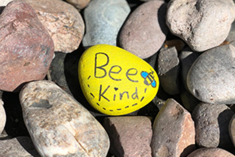 A stone painted with the words 'be kind'