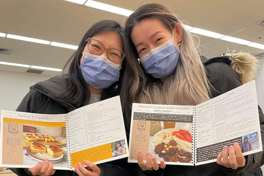 two women hold up copies of a recipe book