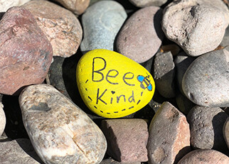 A stone painted with the words 'be kind'